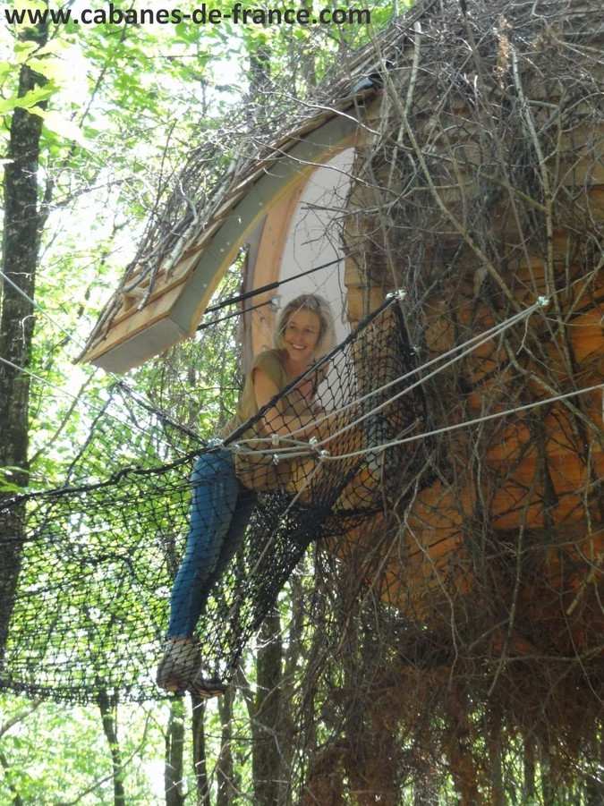 132 Cabane dans les arbres en Aquitaine, entourée de verdure, avec un filet suspendu.