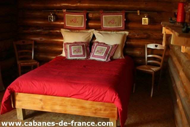 Cabane en bois en Bourgogne, lit douillet avec coussins à motifs.