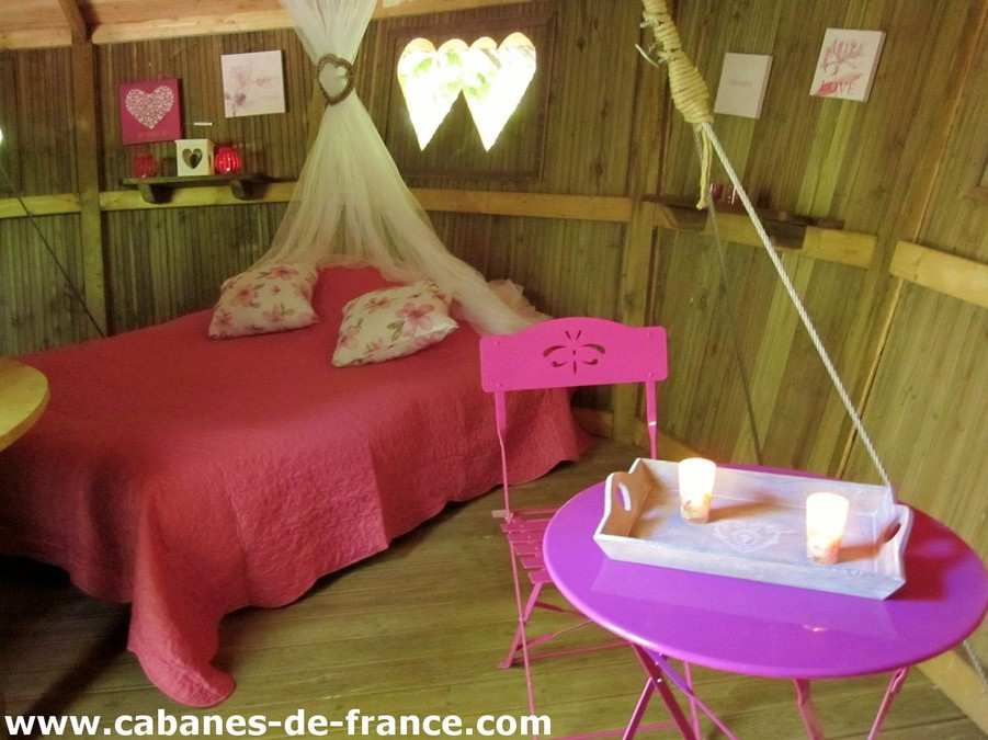 Cabane romantique à Champagne-Ardenne, avec lit douillet et mobilier coloré.