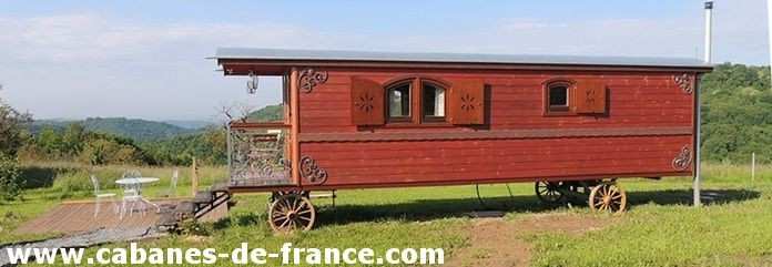 Charmante roulotte en bois avec fenêtres fleuries, entourée de verdure.