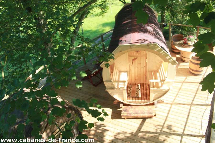 1839 Hébergement insolite en Basse-Normandie : cabane en bois sur plateforme, entourée de verdure.