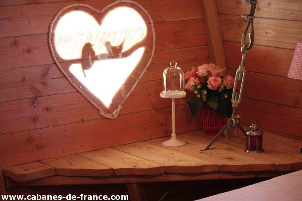 2057 Cabane romantique en Hauts-de-France, avec fenêtre en forme de cœur et fleurs.