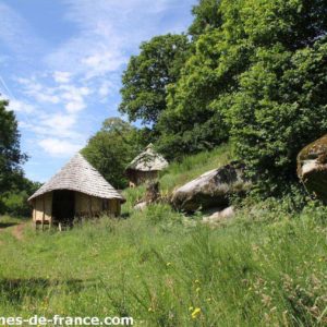 Cabane en bois au milieu de la nature, entourée de verdure et de rochers.