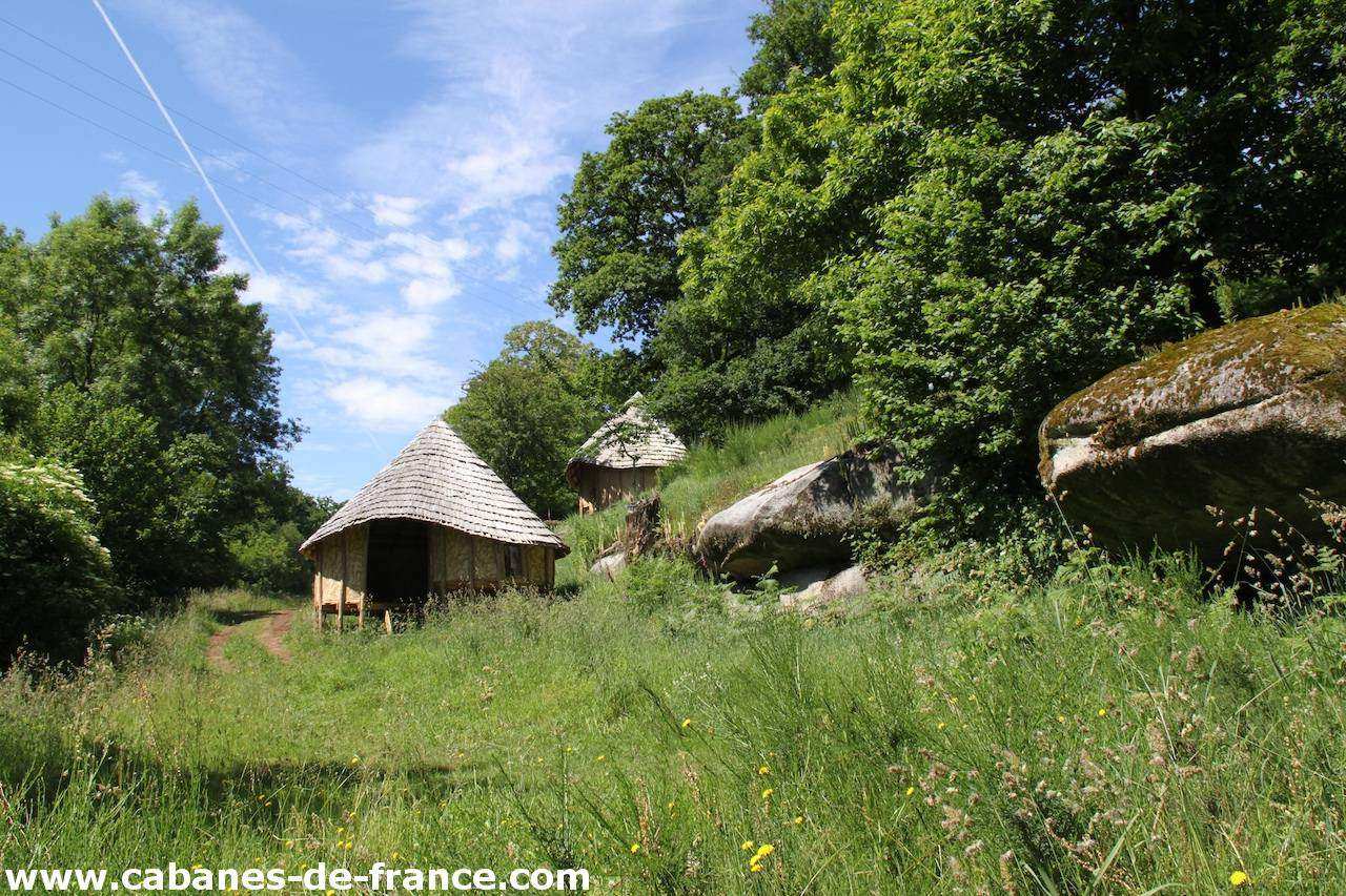 2198 Cabanes en bois au cœur de la nature, entourées de verdure et de rochers.