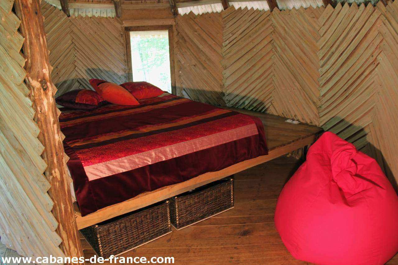 2200 Cabanes dans les arbres en Pays de la Loire, lit douillet avec coussins colorés.
