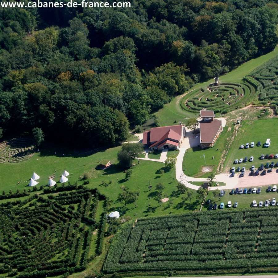 Cabanes en pleine nature avec vue sur un jardin labyrinthique verdoyant.