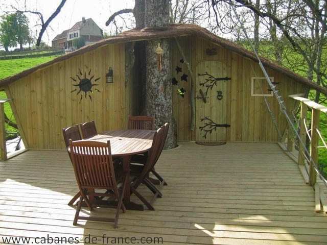 Cabane perchée en Bourgogne, avec terrasse en bois et vue sur la nature environnante.