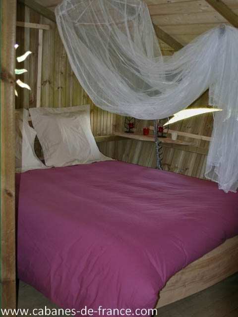 284 Cabane en bois en Bourgogne, lit douillet avec drap rose et voilages légers.