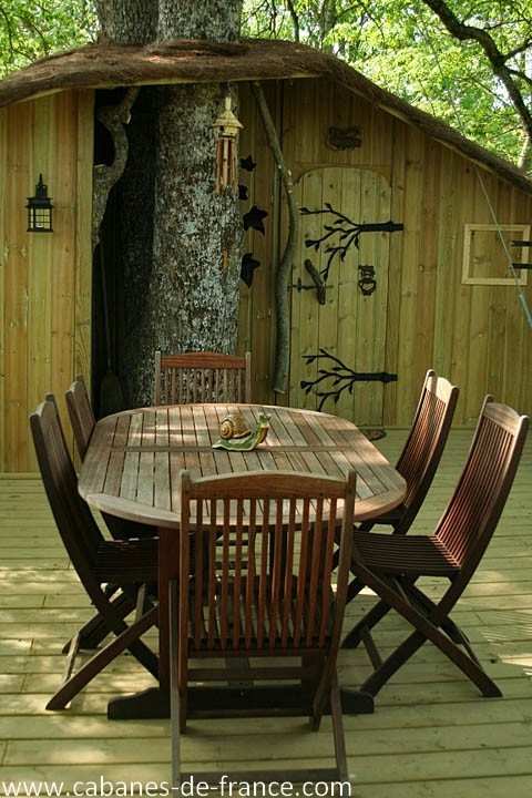 285 Cabane en bois dans un arbre, avec une terrasse et une table en bois accueillante.
