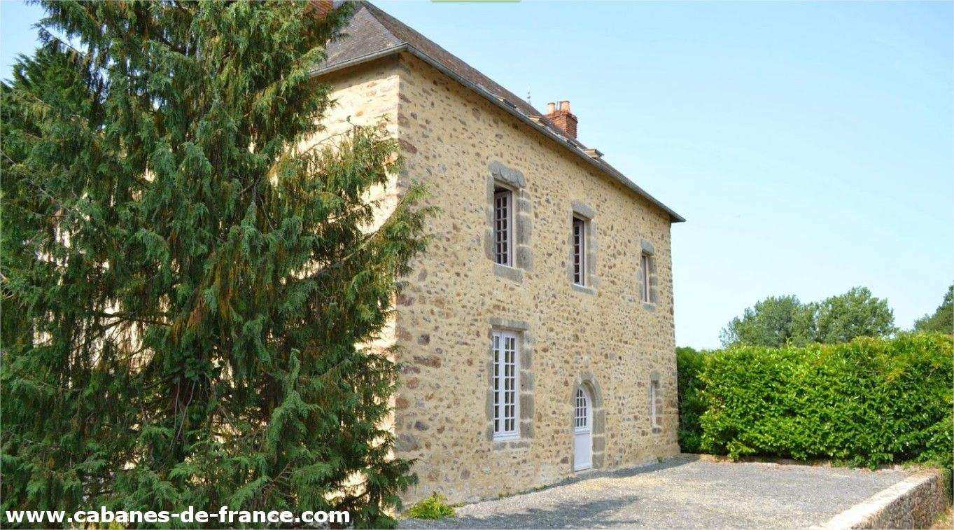 Charmante maison en pierre avec un jardin verdoyant et des fenêtres lumineuses.