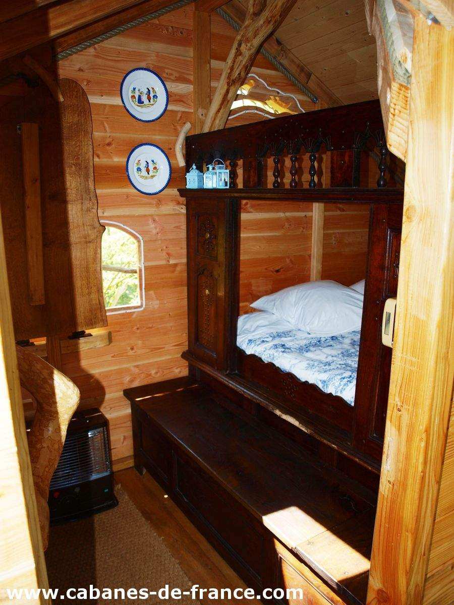 3019 Cabane en bois en Bretagne, avec un lit douillet et des assiettes décoratives au mur.