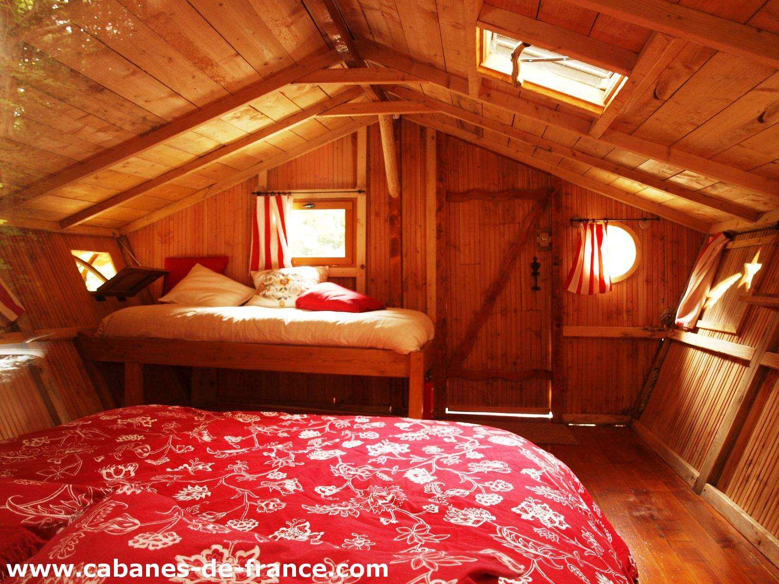 Cabane en bois en Bretagne, intérieur chaleureux avec lits douillets et fenêtres rondes.
