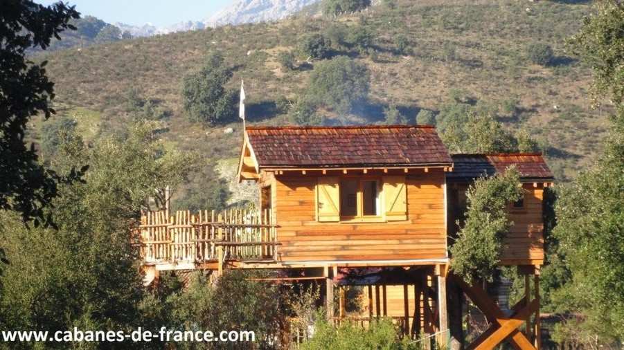 304 Cabane en bois perchée, entourée de verdure, offrant une vue sur les montagnes corses.