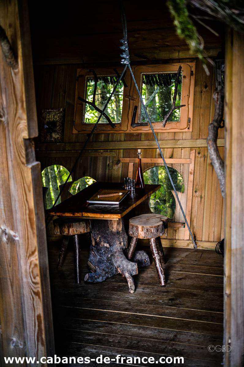 3070 Cabane en bois en Bretagne, avec une table rustique et des chaises en troncs darbre.