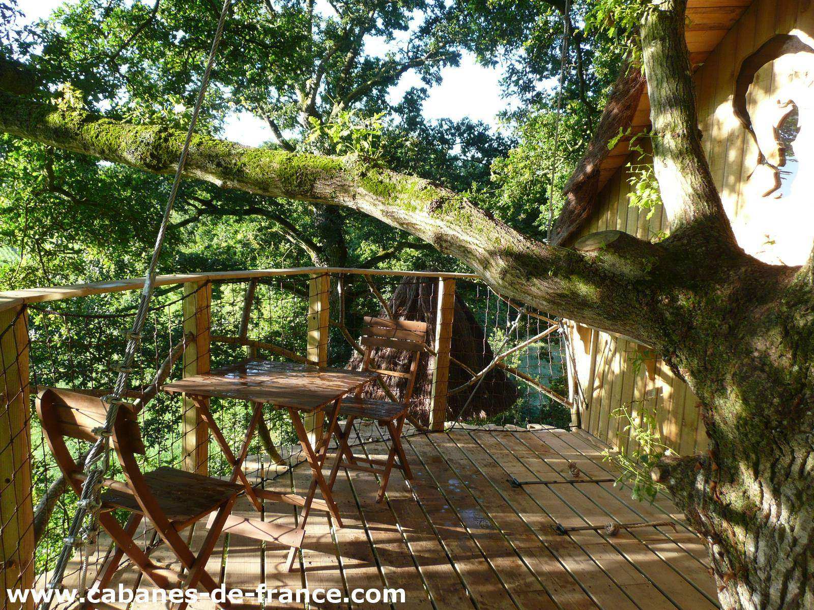 3077 Cabane dans les arbres en Bretagne, avec terrasse en bois et vue sur la nature.