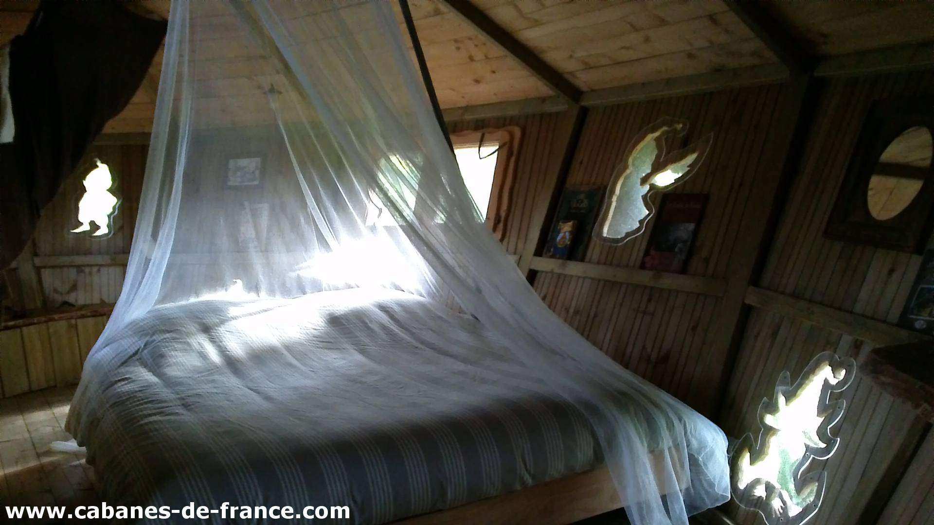 3079 Cabane en bois en Bretagne, lit avec moustiquaire et décor naturel.