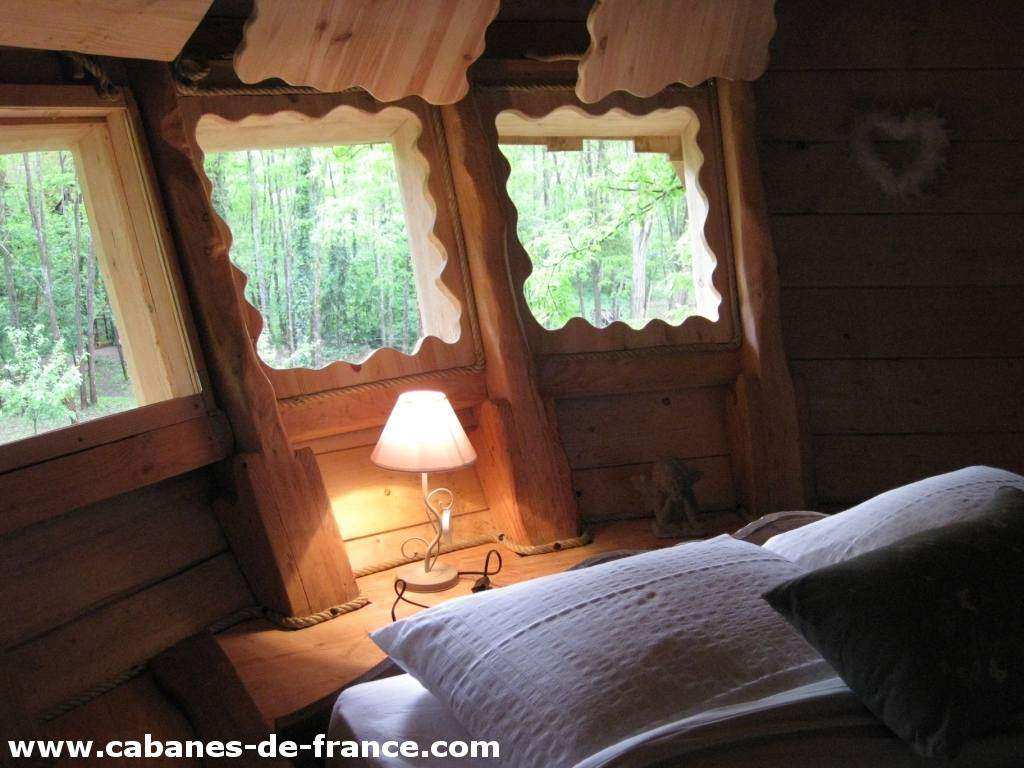 3416 Cabane perchée avec fenêtres en bois, offrant une vue sur la forêt verdoyante.