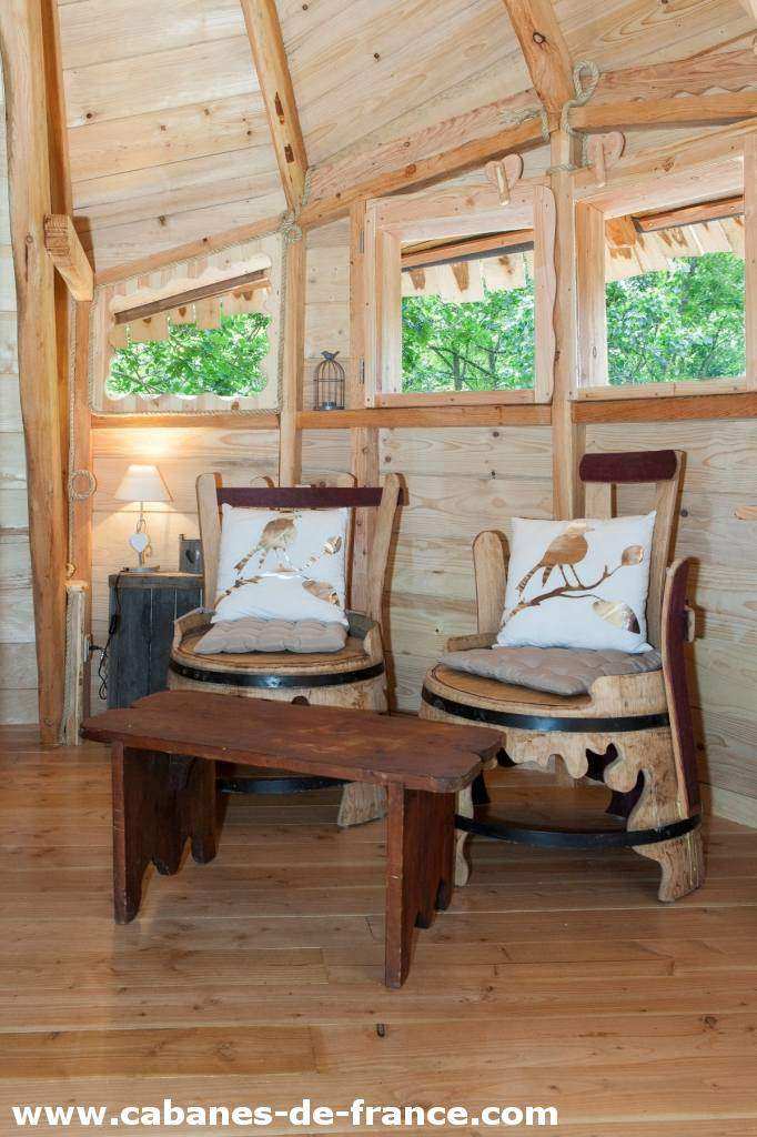 3418 Intérieur chaleureux dune cabane en bois avec chaises confortables et table en bois.