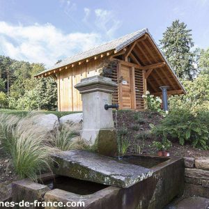 Cabane en bois au milieu de la nature, avec un joli point deau à proximité.