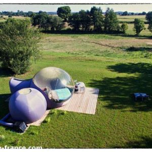 Hébergement insolite en bulle transparente, entouré de verdure et despace.