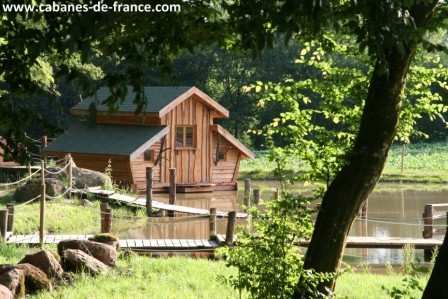 485 Cabane en bois flottant entourée darbres, au bord dun étang paisible.