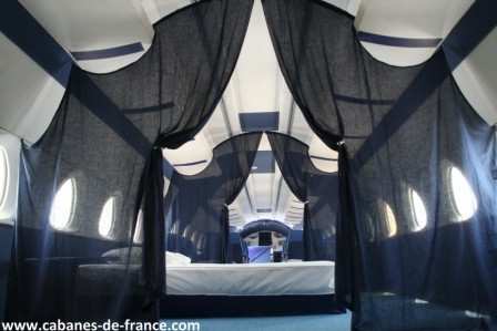 497 Intérieur dune cabane insolite à Grand-Est, avec des rideaux noirs et des fenêtres arrondies.