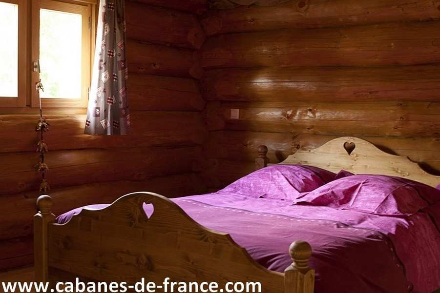 743 Chalet en bois avec lit en bois sculpté et draps violets, ambiance chaleureuse.