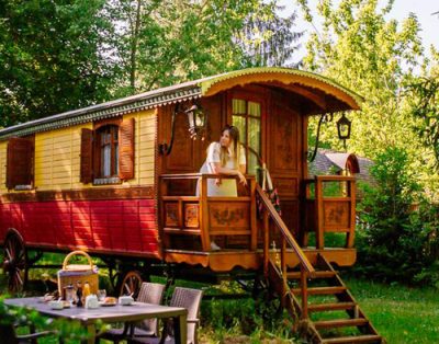 Charmante roulotte en bois, entourée de verdure, avec terrasse accueillante.