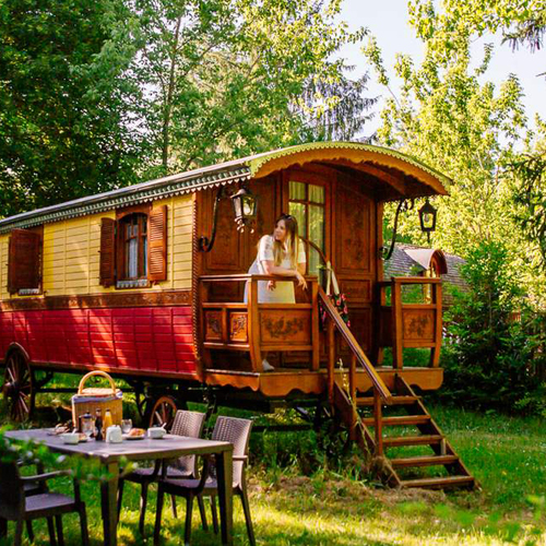 CC-Nomade-photo4 Charmante roulotte en bois, entourée de verdure, avec terrasse accueillante.