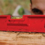 Hébergement en bois, un artisan vérifie lhorizontalité avec un niveau rouge.
