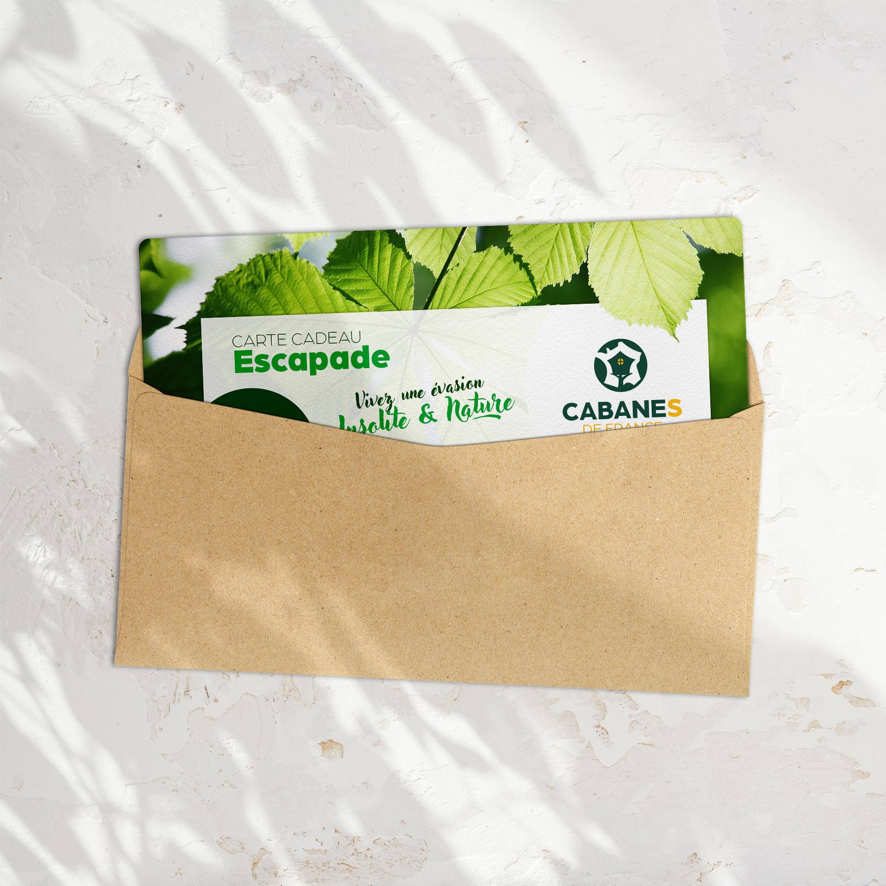 CC-Escapade-mockup Carte cadeau pour des cabanes en pleine nature, enveloppe décorée de feuilles.