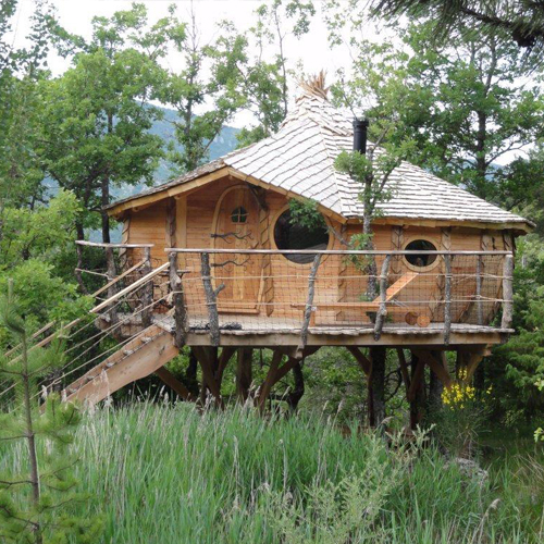 CC-Escapade-photo5 Cabane dans les arbres en bois, perchée au milieu de la verdure luxuriante.