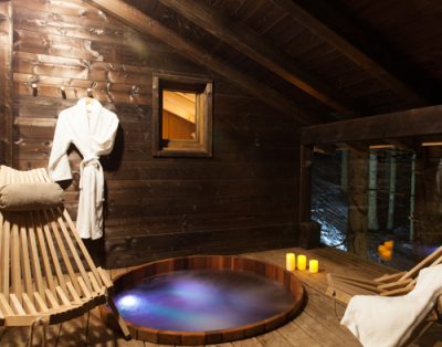 Chalet en bois avec jacuzzi, ambiance chaleureuse et éclairage doux.