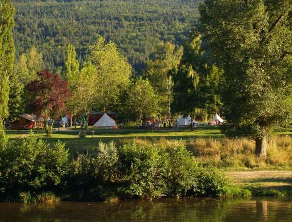Camping au bord dun lac, tentes entourées darbres verdoyants et paisibles.