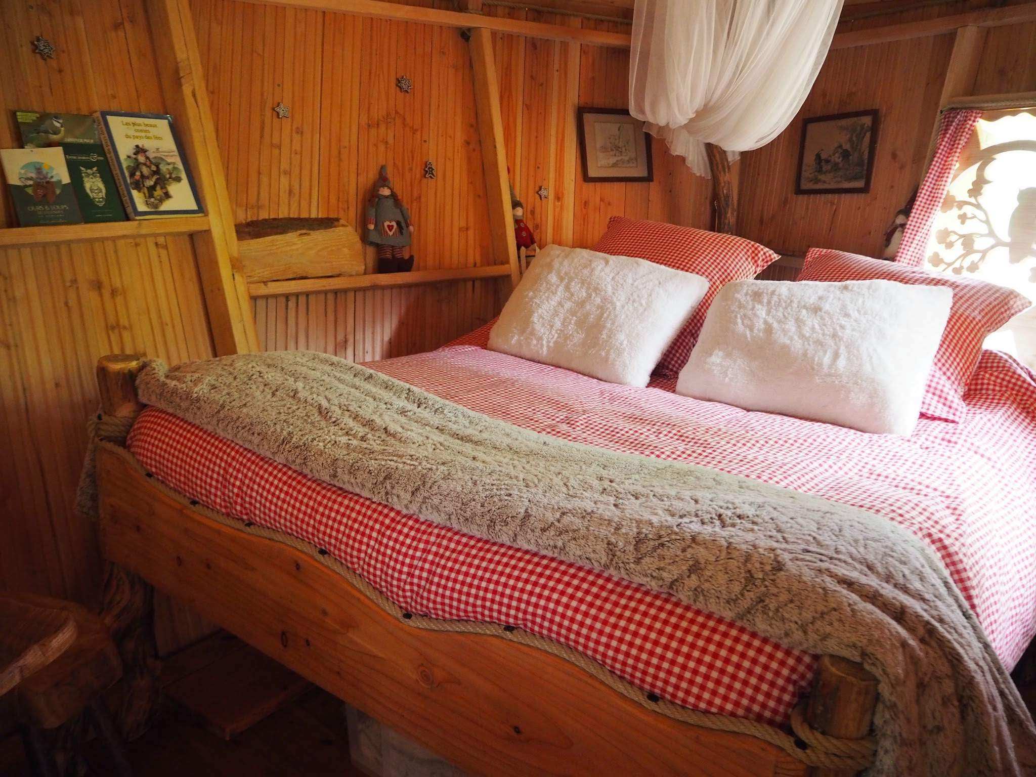 4291 Cabane en bois avec lit douillet, draps à carreaux rouges et ambiance chaleureuse.