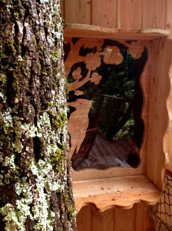 4296 Cabane perchée en bois avec fenêtre sculptée, nichée dans un arbre en Auvergne.