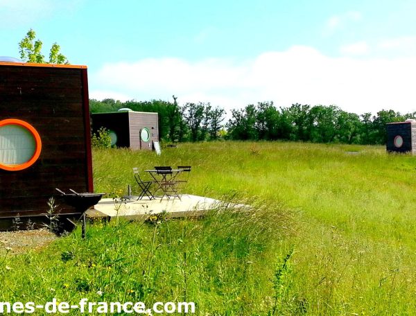 Cabanes modernes en pleine nature, entourées de verdure et avec terrasses privées.