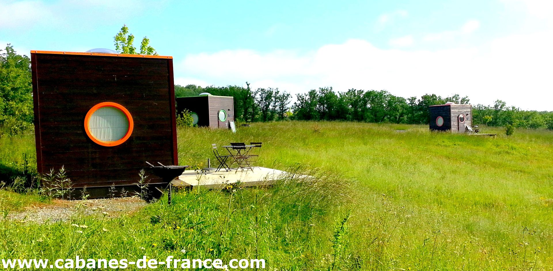 Cabanes modernes en pleine nature, entourées de verdure et avec terrasses privées.
