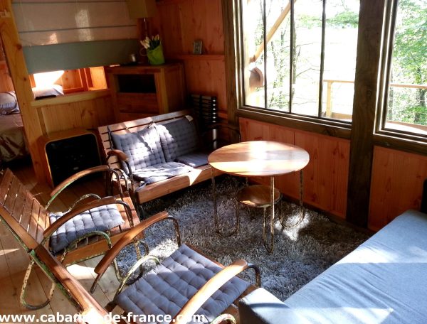 Cabane en bois avec un salon lumineux et des fauteuils confortables.