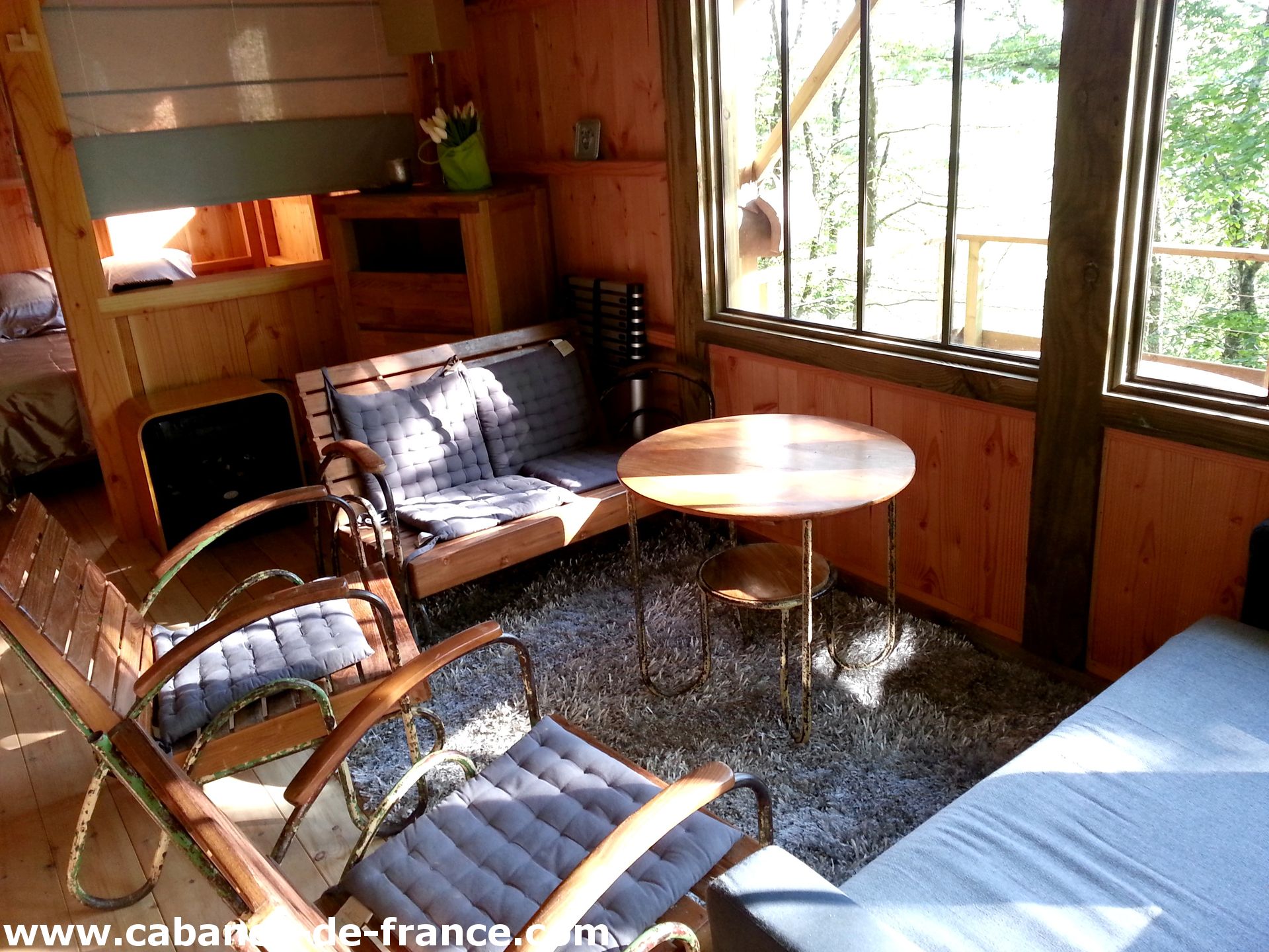 Cabane en bois avec un salon lumineux et des fauteuils confortables.