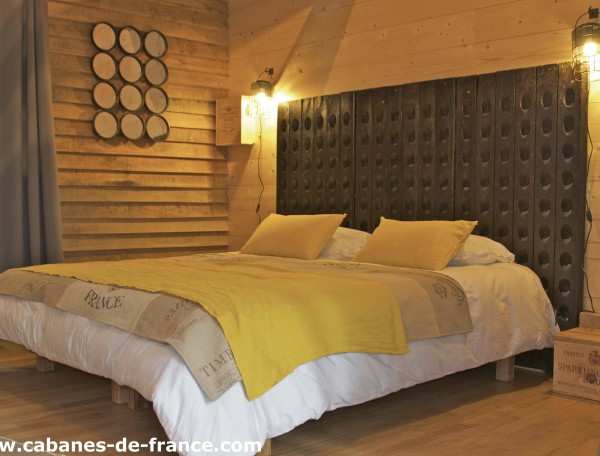 Chalet en bois avec un lit douillet et des murs en panneaux de bois chaleureux.
