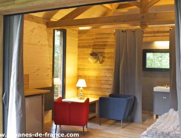Cabane en bois avec un coin salon cosy et une lumière chaleureuse.