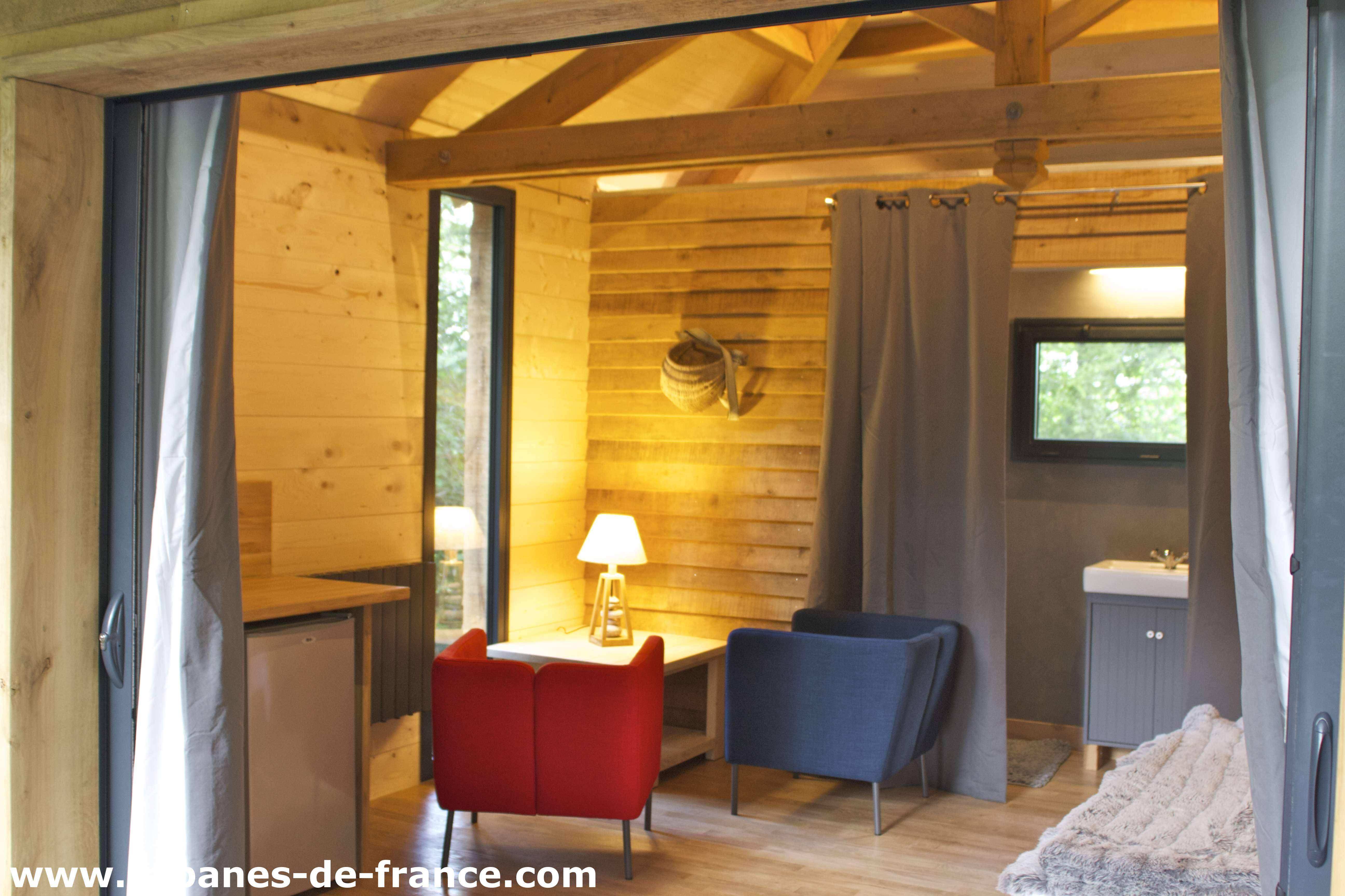 Cabane en bois avec un coin salon cosy et une lumière chaleureuse.