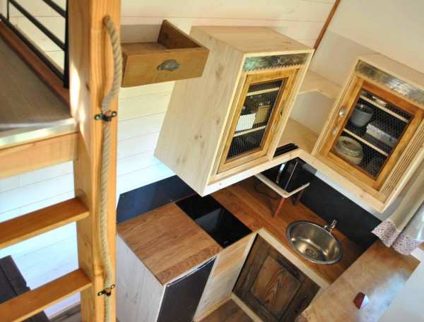 Cabane en bois avec cuisine équipée et mezzanine lumineuse.