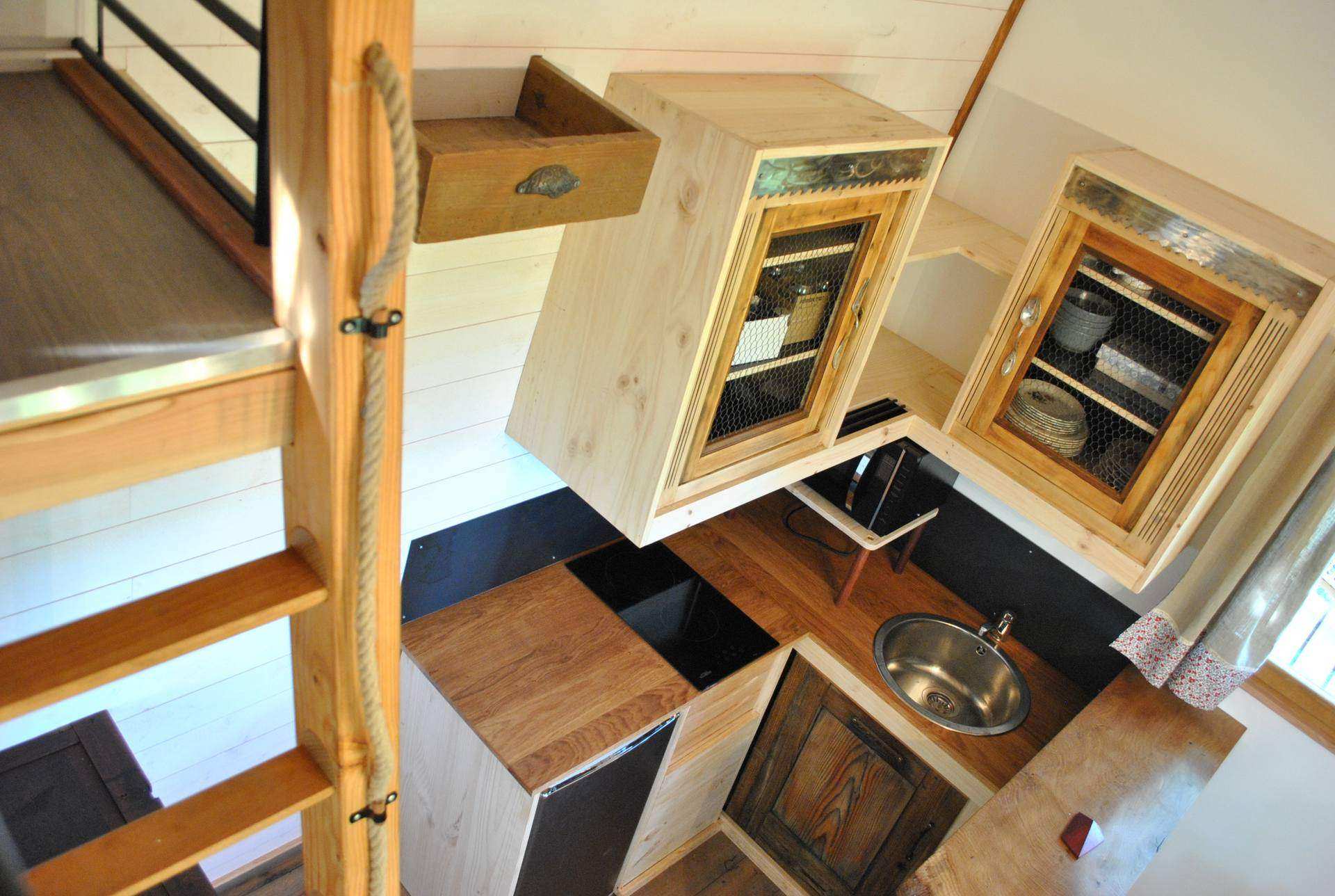 Cabane en bois avec cuisine équipée et mezzanine lumineuse.