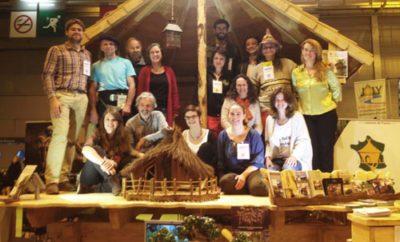 Groupe de personnes devant un chalet en bois, représentant un hébergement touristique.