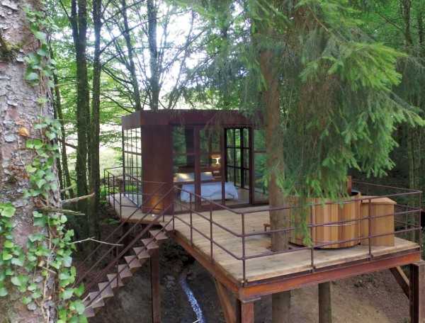 Cabane perchée en Aquitaine, entourée darbres, avec terrasse et vue dégagée.