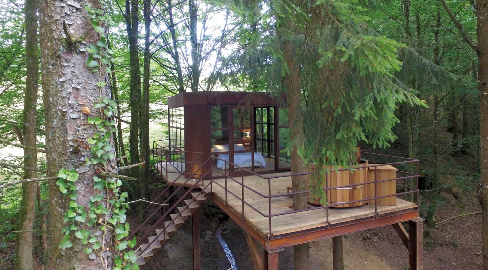 Cabane perchée en Aquitaine, entourée darbres, avec terrasse et vue dégagée.