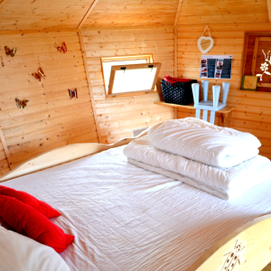 Chalet en bois chaleureux avec lit douillet et décorations colorées.