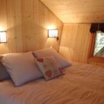 Cabane en bois avec un lit douillet et des lampes murales chaleureuses.